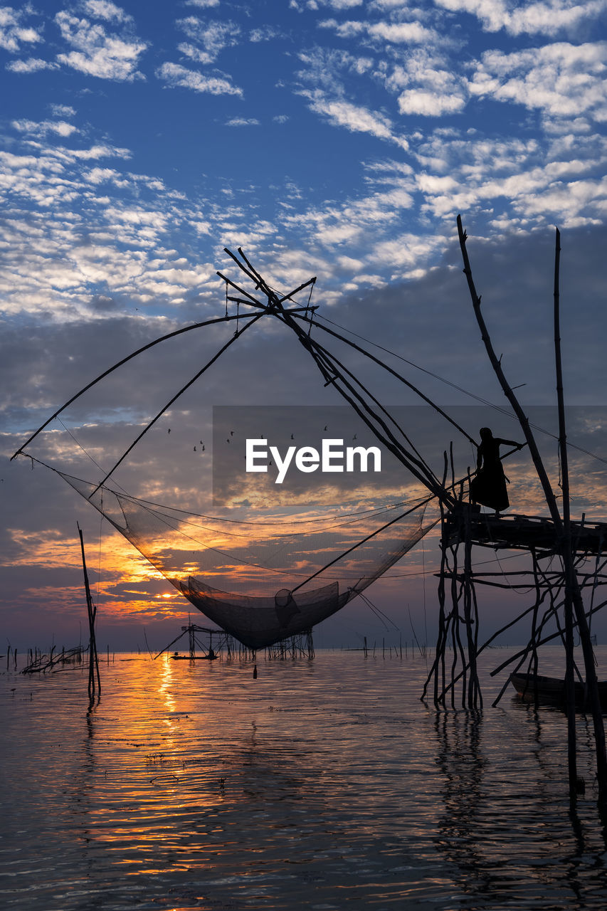 SILHOUETTE OF FISHING BOAT IN SEA AGAINST SKY DURING SUNSET