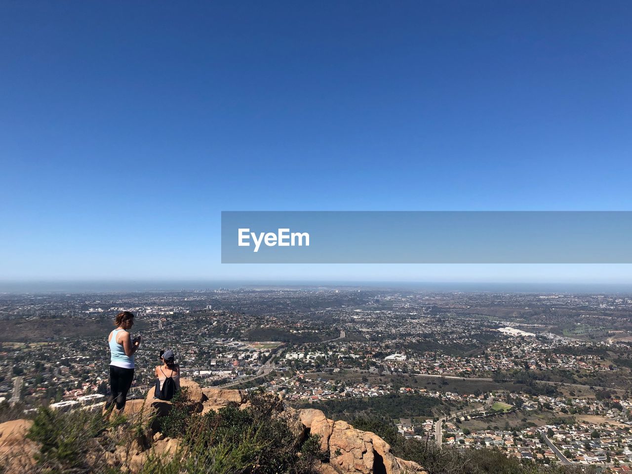 PEOPLE LOOKING AT CITY AGAINST CLEAR BLUE SKY