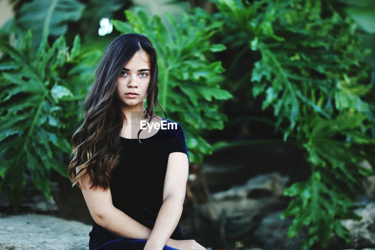 Portrait of beautiful young woman against plants