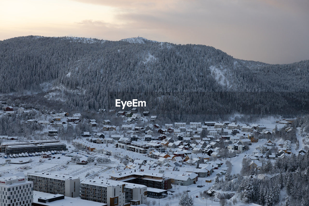 winter, snow, cold temperature, architecture, landscape, mountain, environment, building, scenics - nature, building exterior, sky, built structure, nature, house, tree, beauty in nature, residential district, land, city, no people, mountain range, plant, travel destinations, cloud, high angle view, travel, forest, outdoors, sunset, tourism, village, tranquility, frozen, tranquil scene, town, coniferous tree, fog