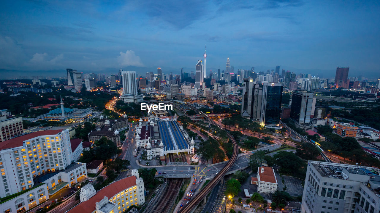 HIGH ANGLE VIEW OF ILLUMINATED CITY AGAINST SKY