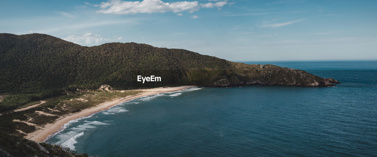 Scenic view of sea by mountains against sky