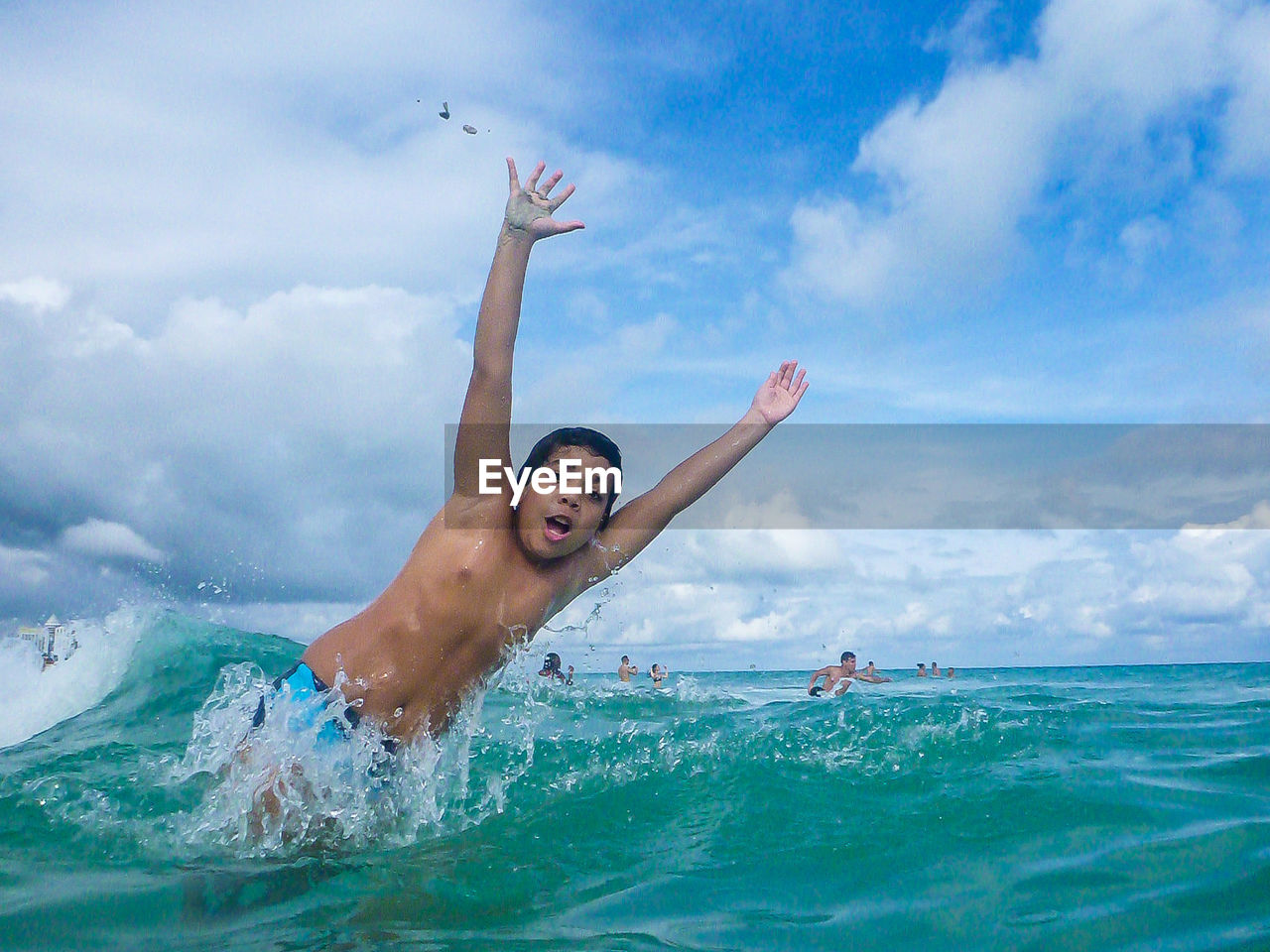 Portrait of shirtless boy jumping on sea against cloudy sky