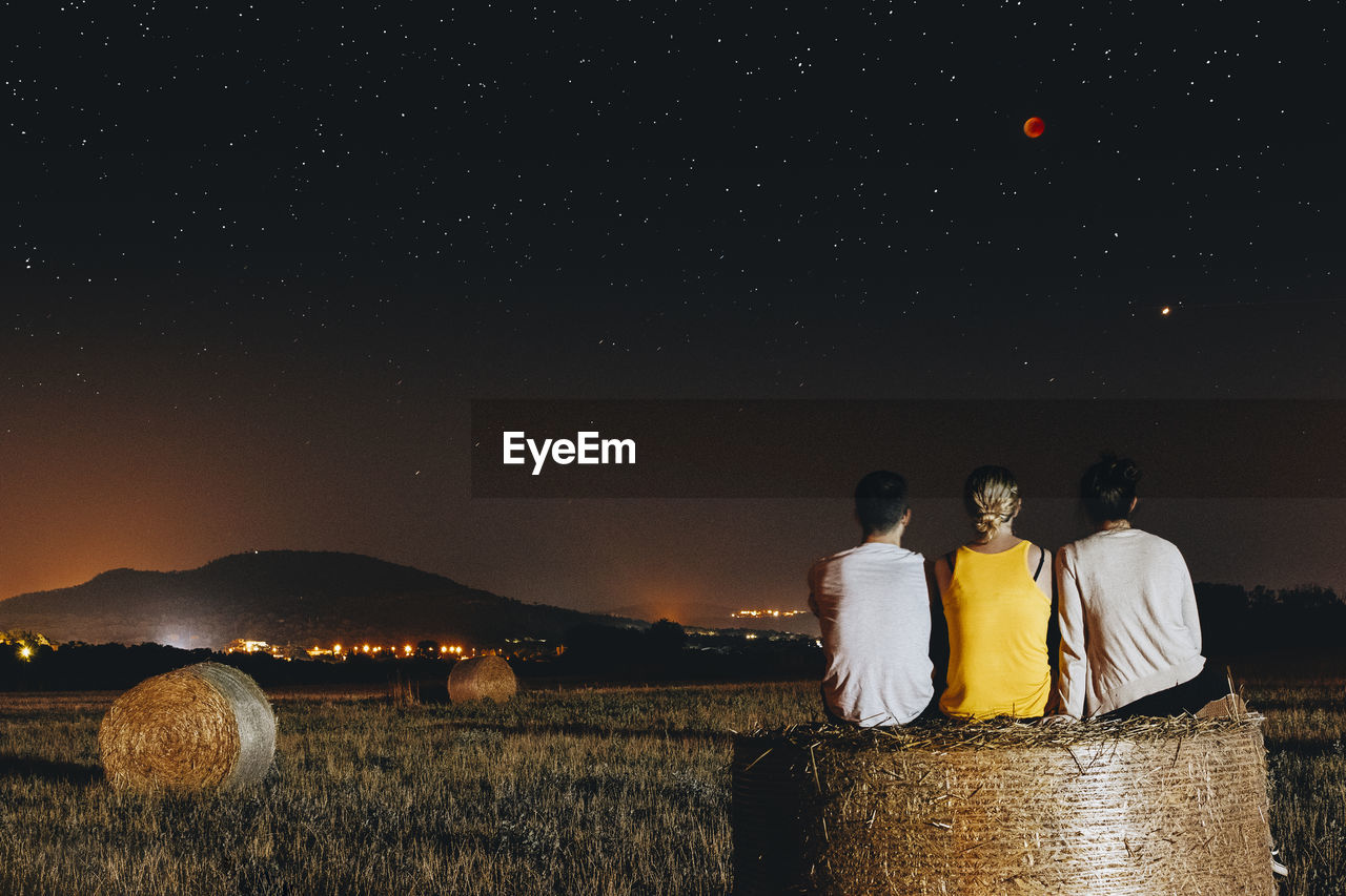 People on field against sky at night