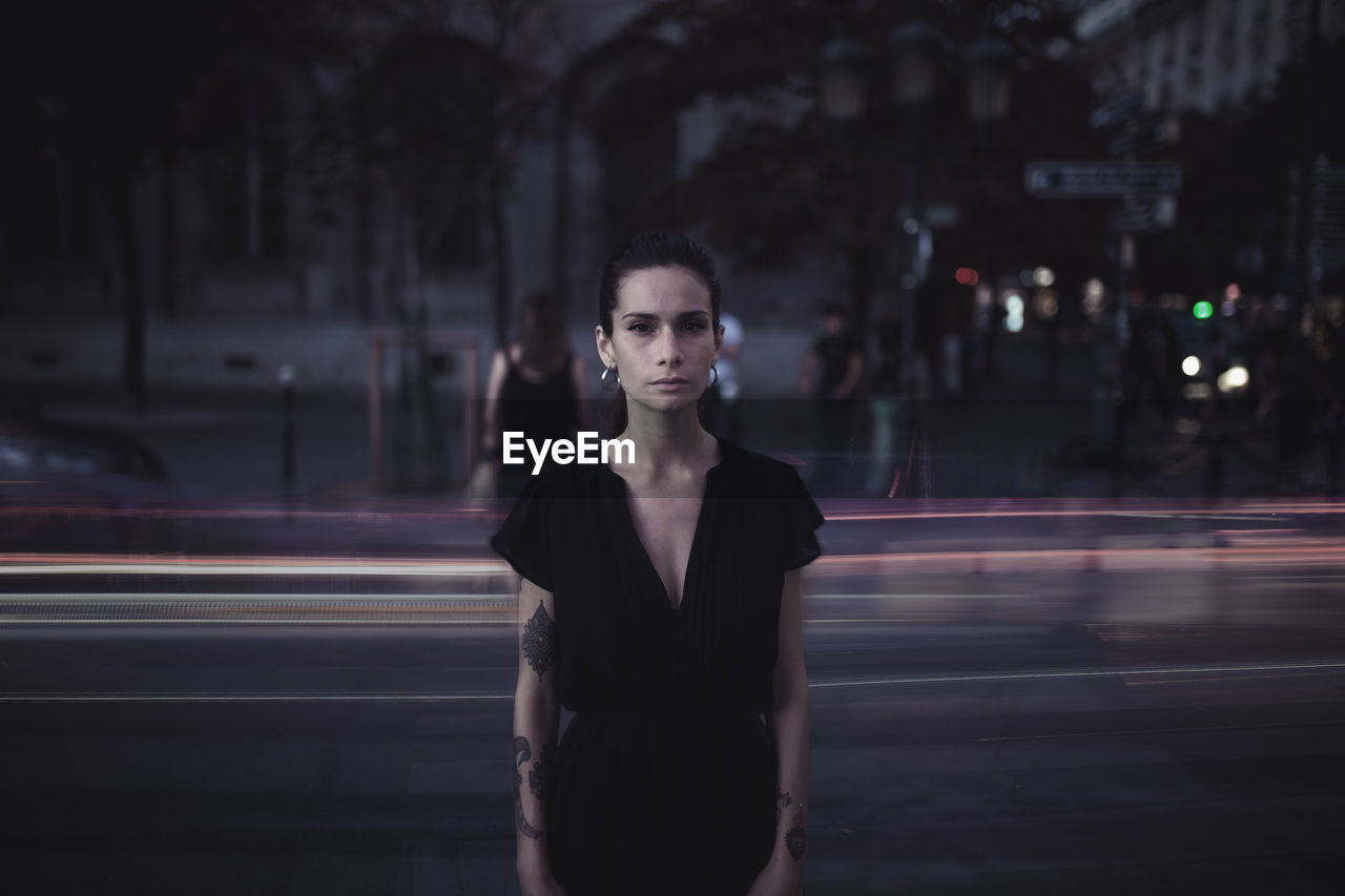 Portrait of woman standing on street at night