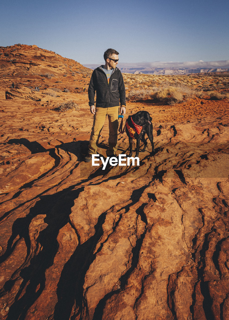 A man with a dog is standing near horseshoe bend, arizona