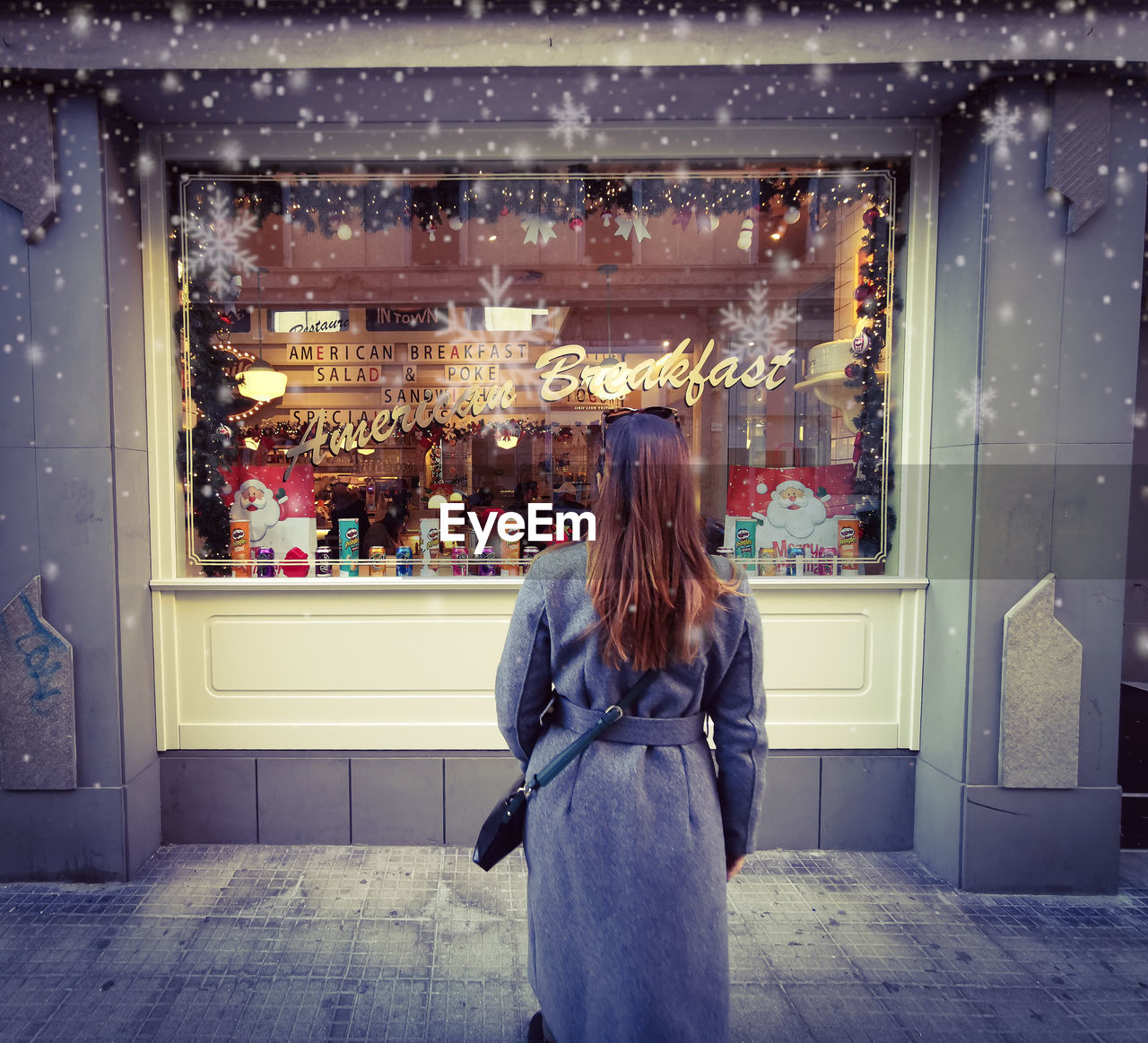 Rear view of woman standing by store on footpath