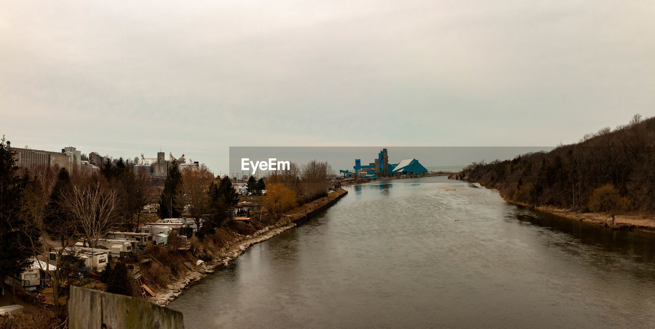 PANORAMIC SHOT OF RIVER AMIDST TREES AGAINST SKY