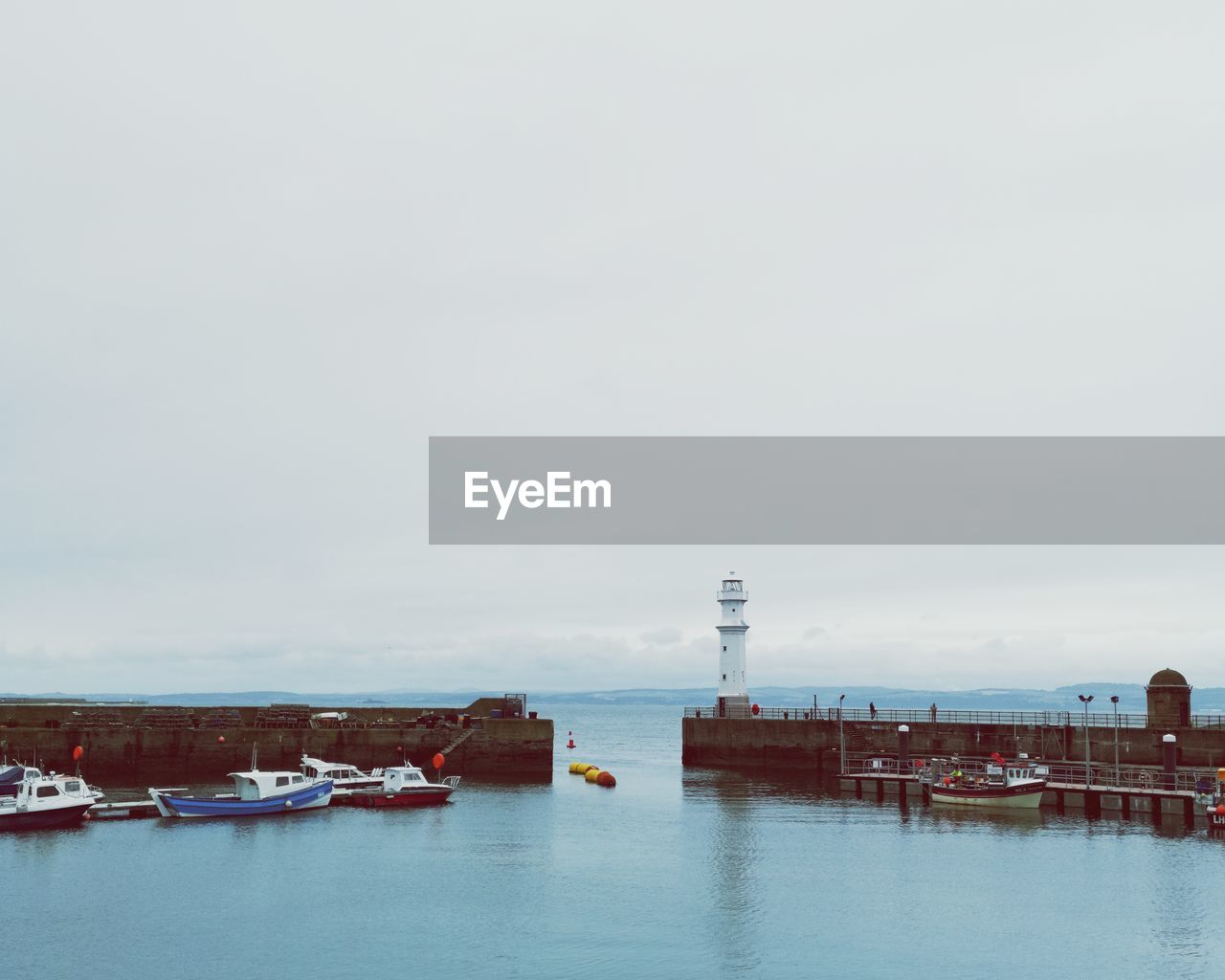 Boats moored at harbor against sky