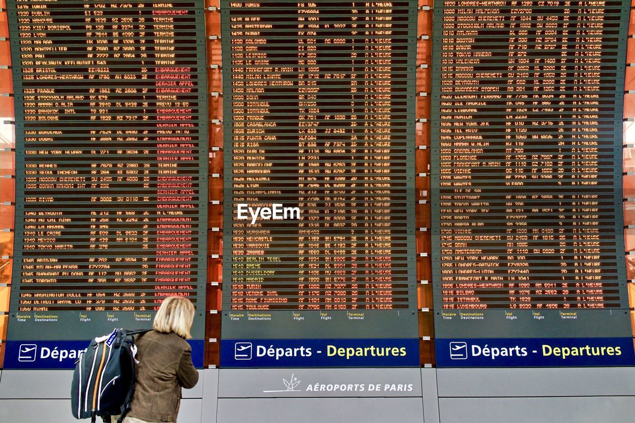 REAR VIEW OF MAN WITH TEXT STANDING ON RAILROAD STATION