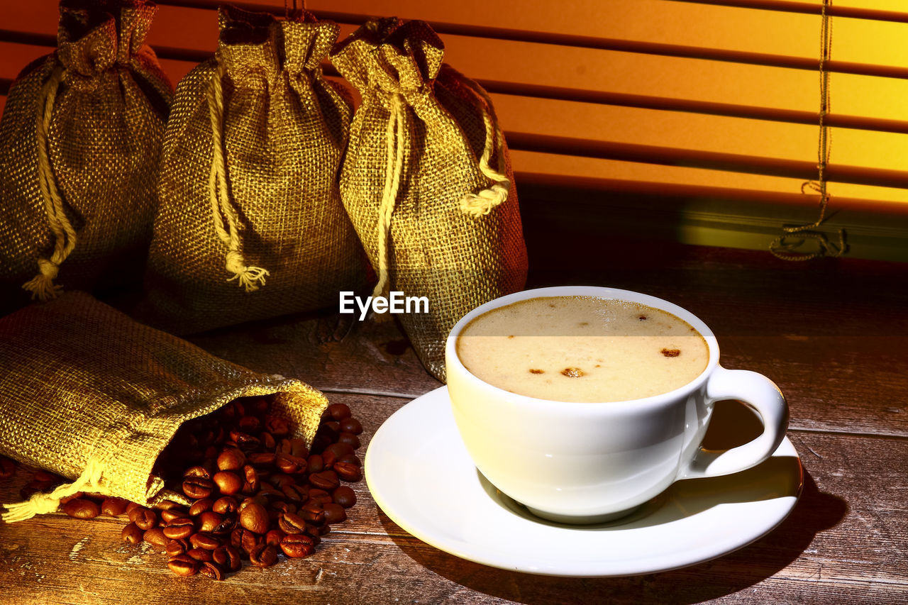 Coffee cup filled with coffee set against a kitchen window blind 