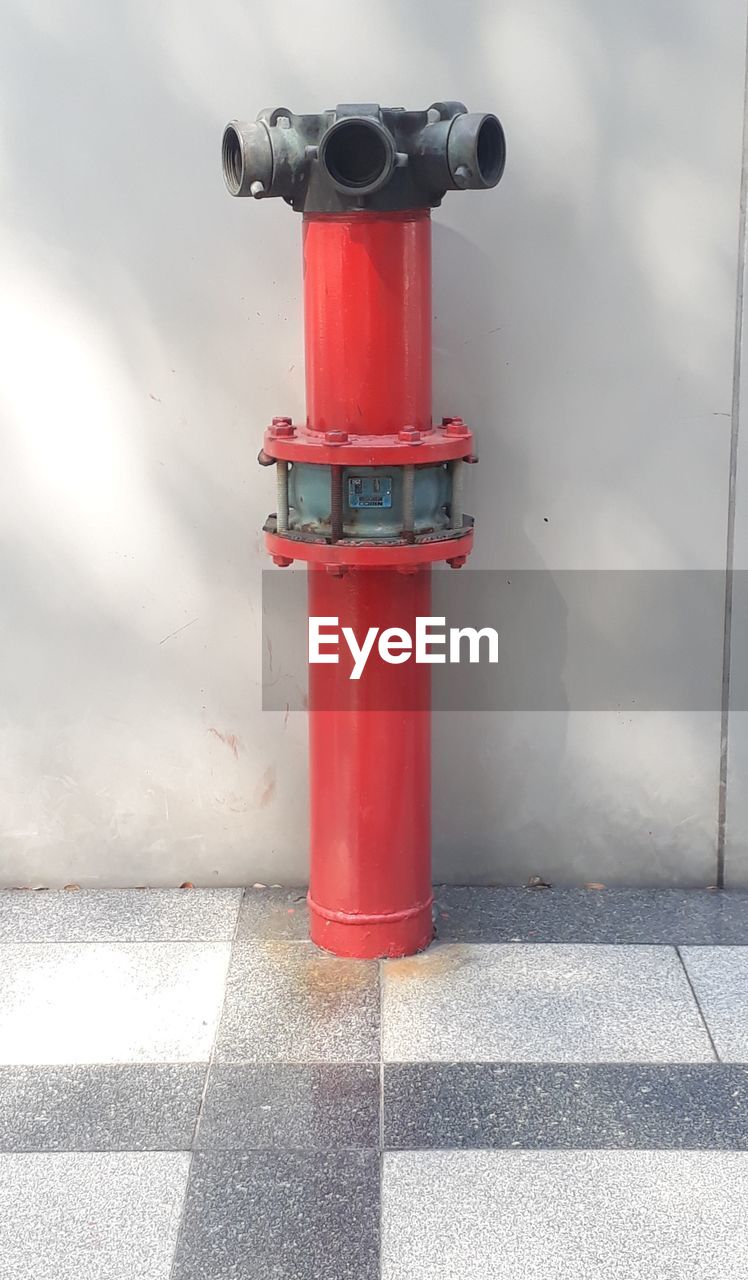 CLOSE-UP OF RED FIRE HYDRANT ON FOOTPATH