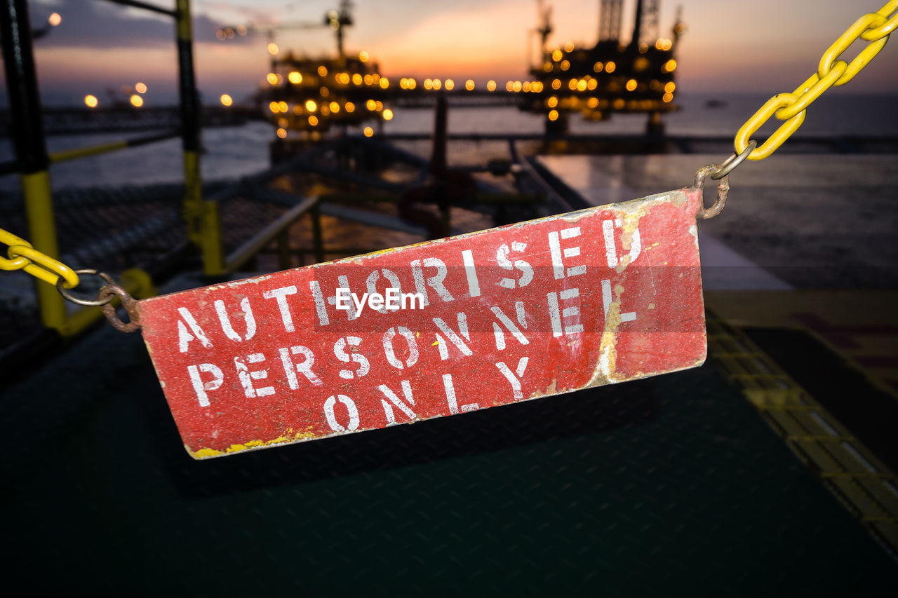 Close-up of safety or warning sign hanging on railing of a construction work barge at oil field