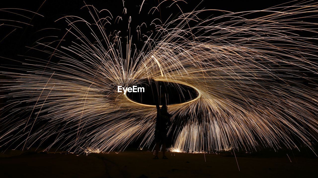 Man spinning wire wool at night