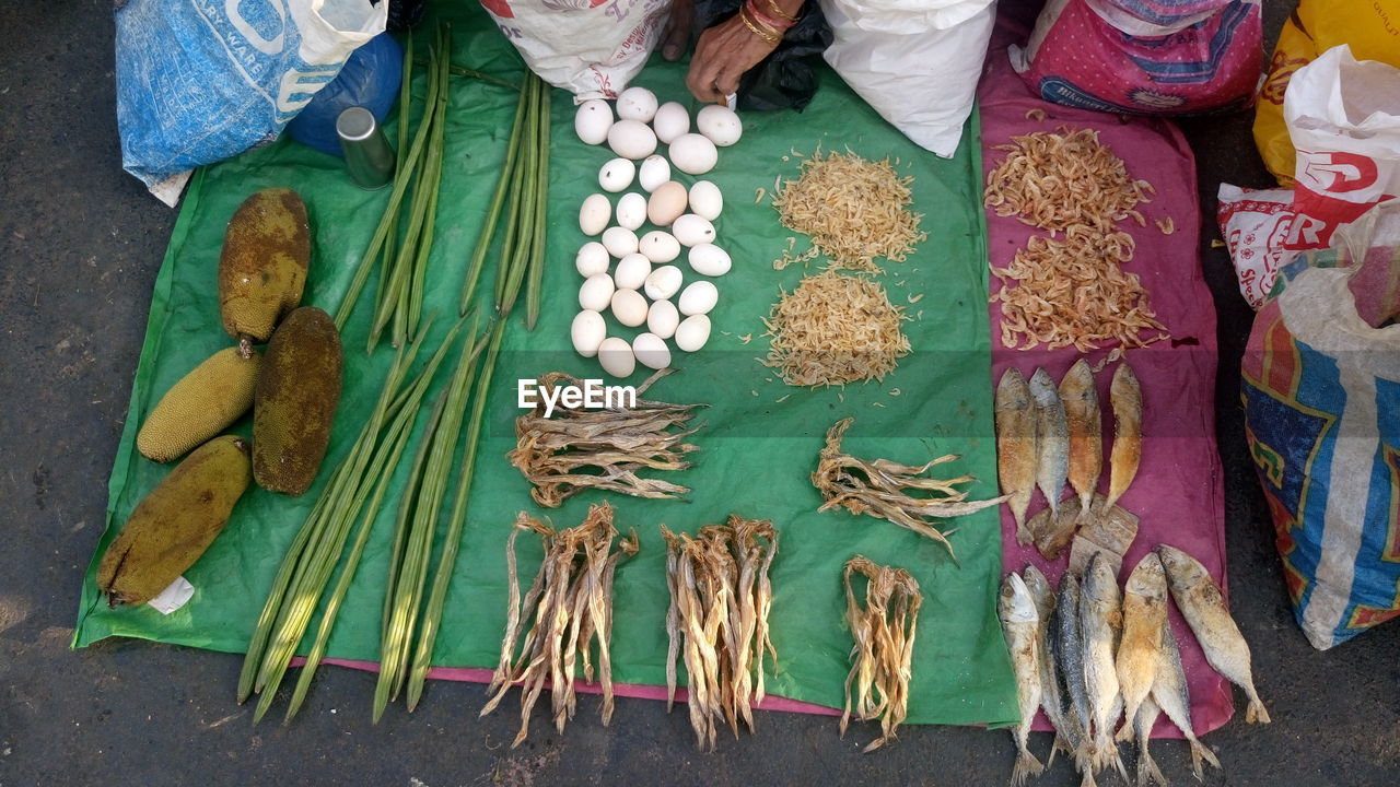 Cropped hand of woman selling dry fish and vegetables at street market