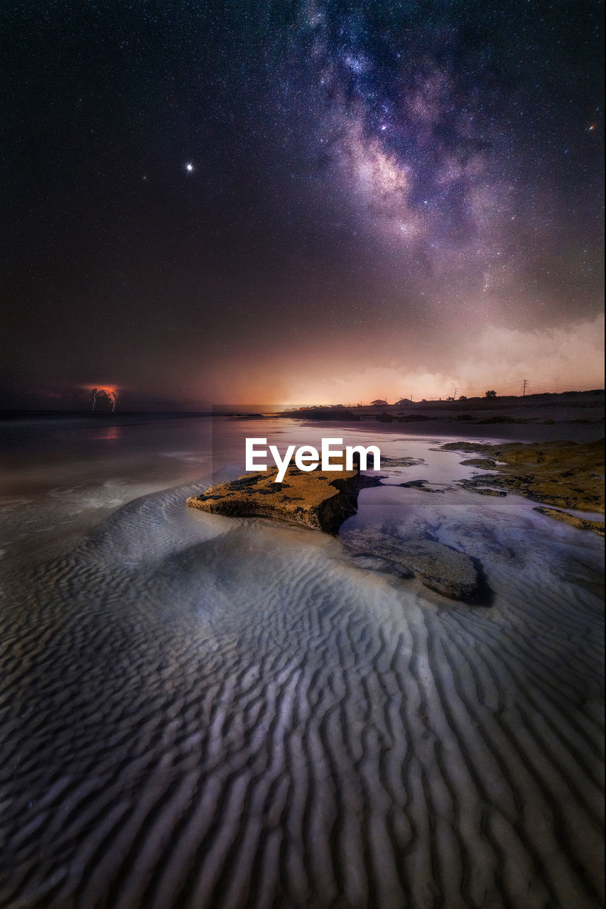 Scenic view of sea against sky and milkyway at night