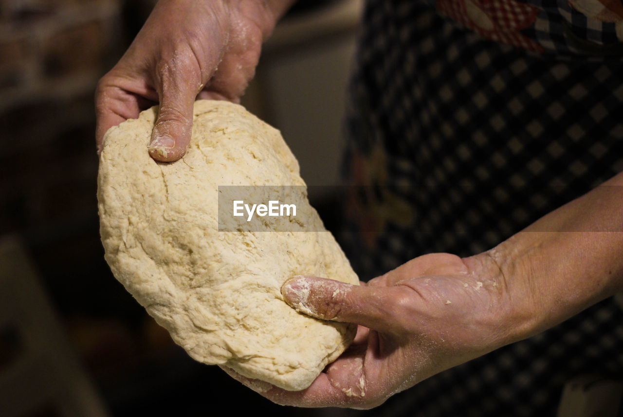 Midsection of person preparing food, holding dough