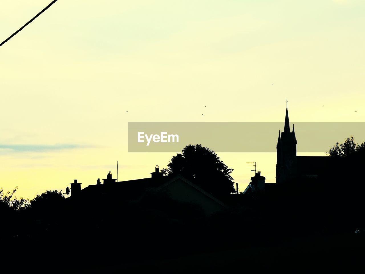 SILHOUETTE TREES AND HOUSES AGAINST SKY AT DUSK