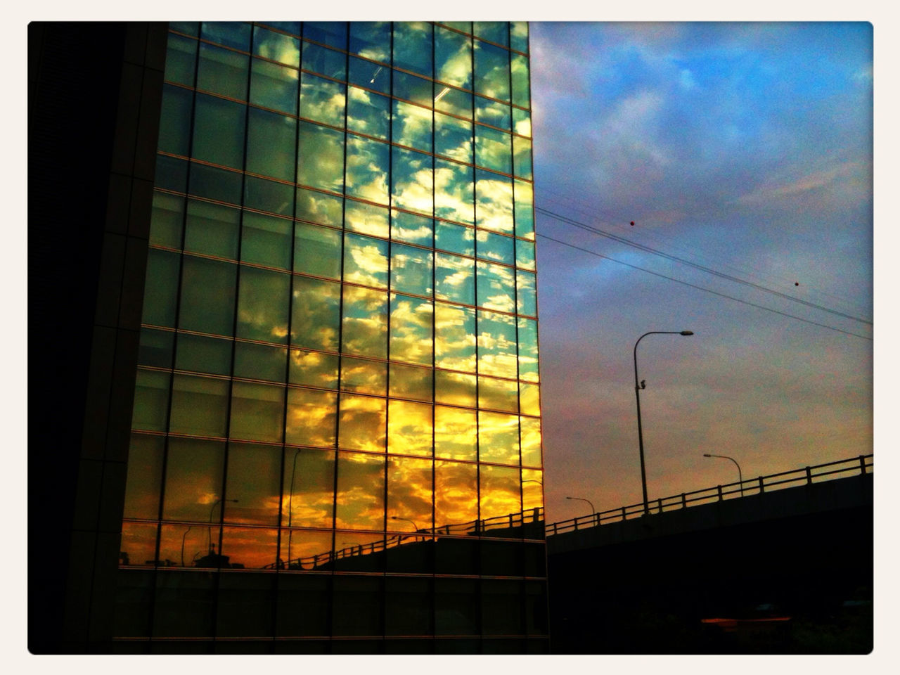 SILHOUETTE OF BUILDING AGAINST CLOUDY SKY AT SUNSET