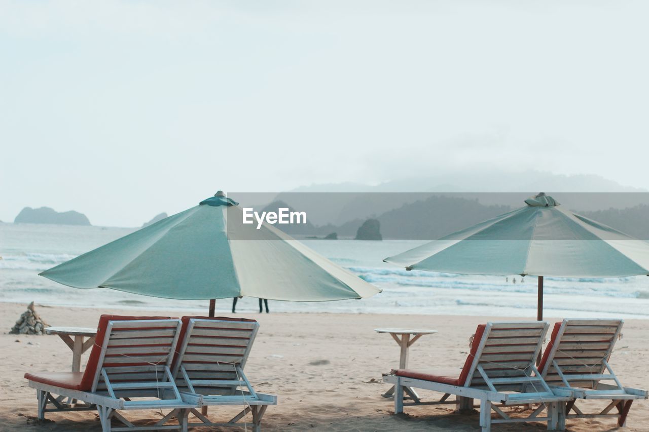 Chairs on beach against clear sky