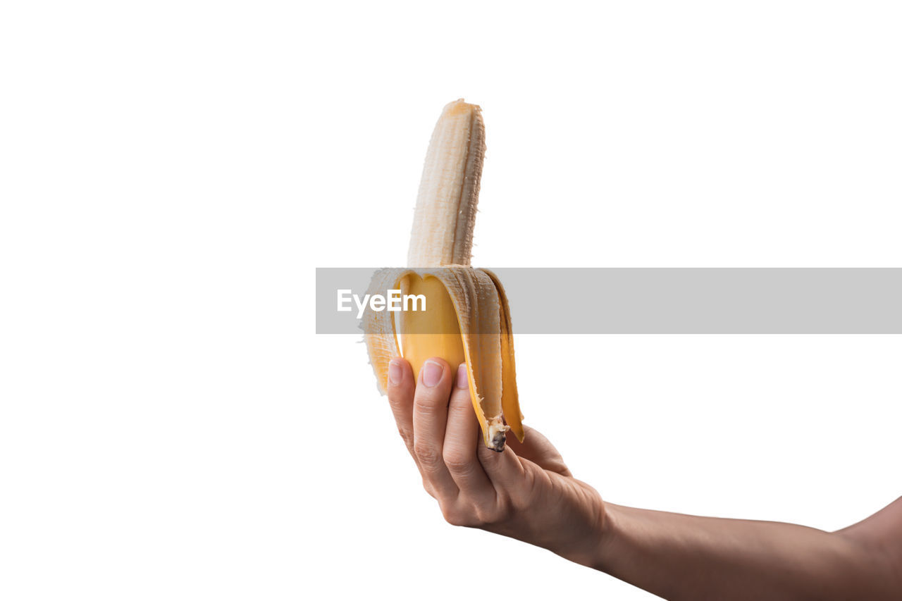 CLOSE-UP OF HAND HOLDING FRUIT OVER WHITE BACKGROUND