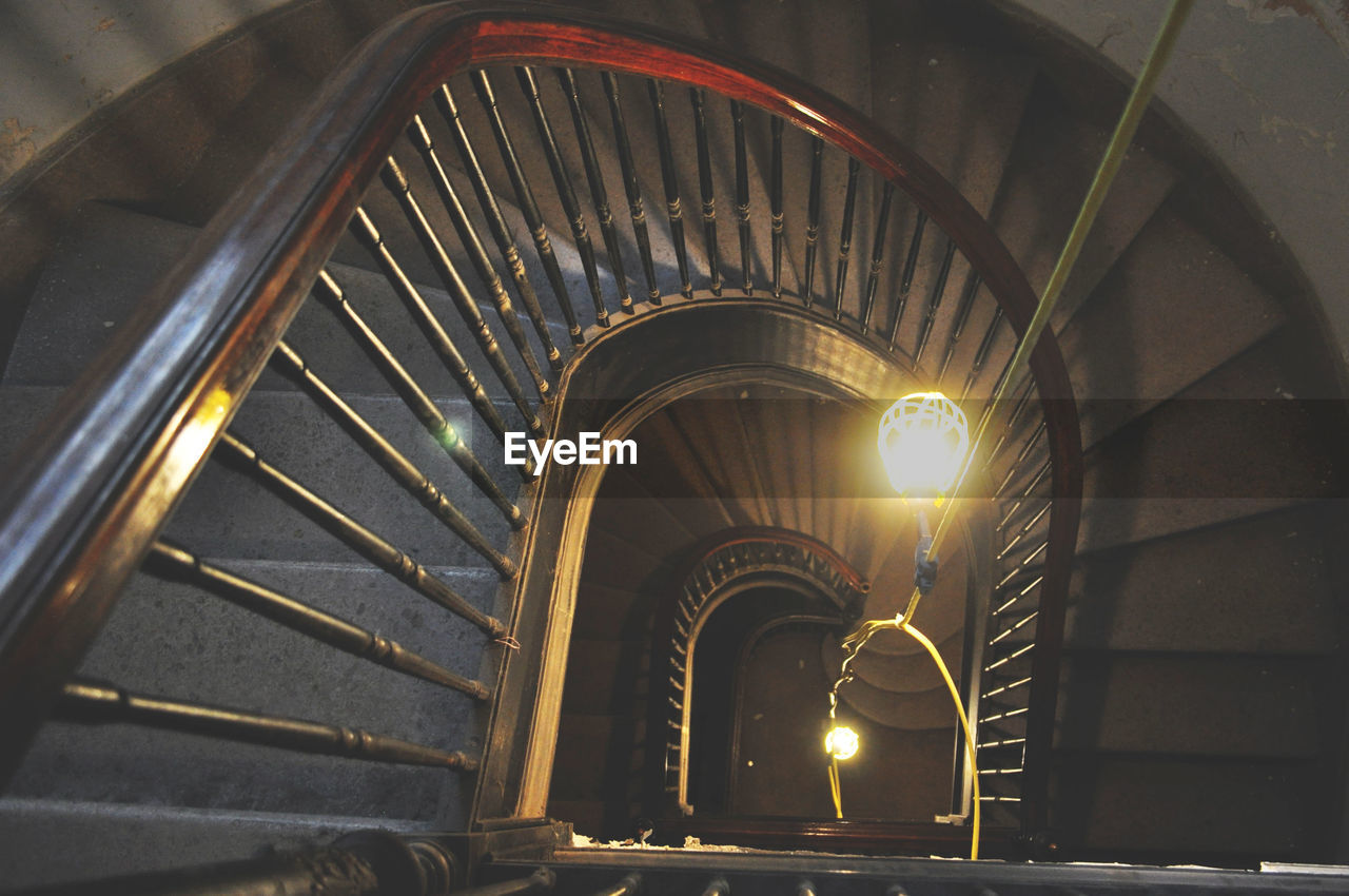 High angle view of lit light bulb by spiral staircases