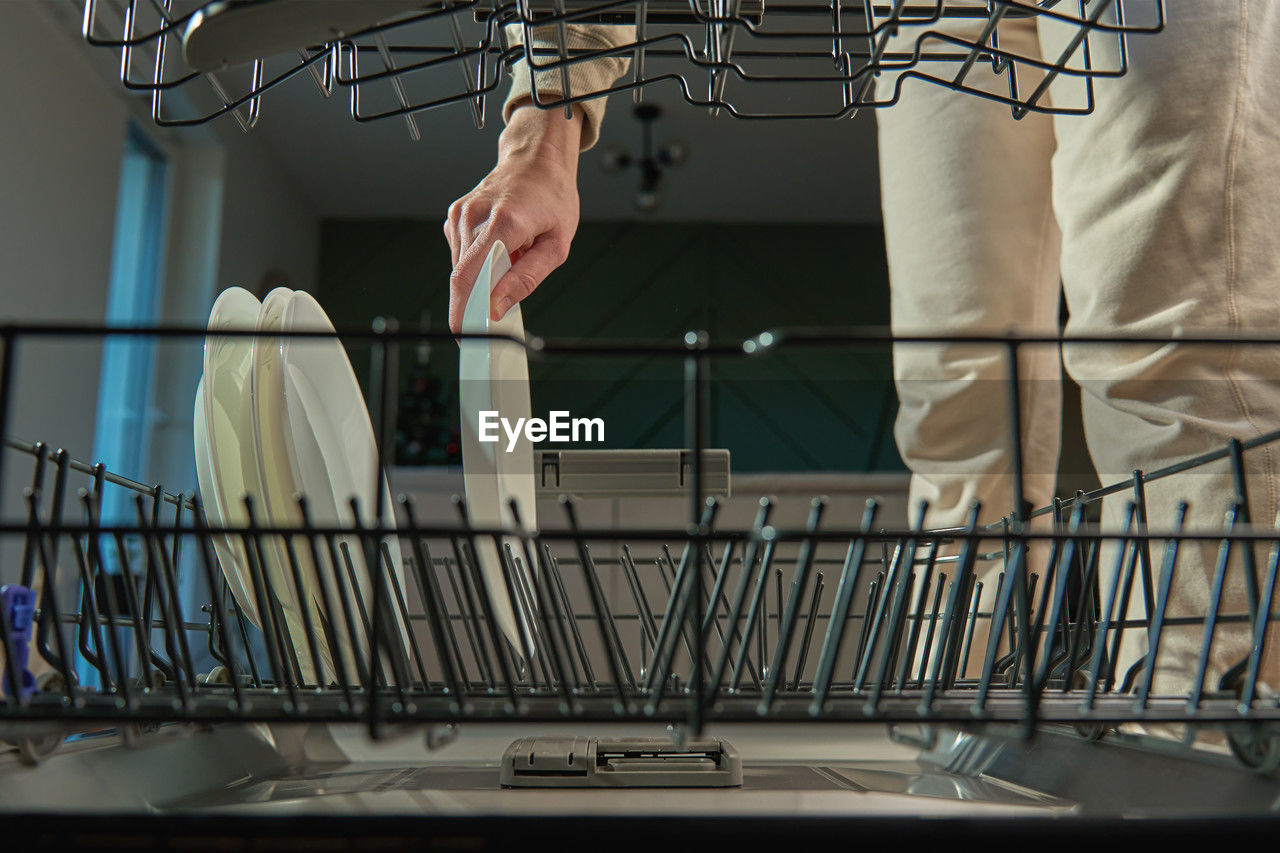 Woman unloading plates from modern dishwasher