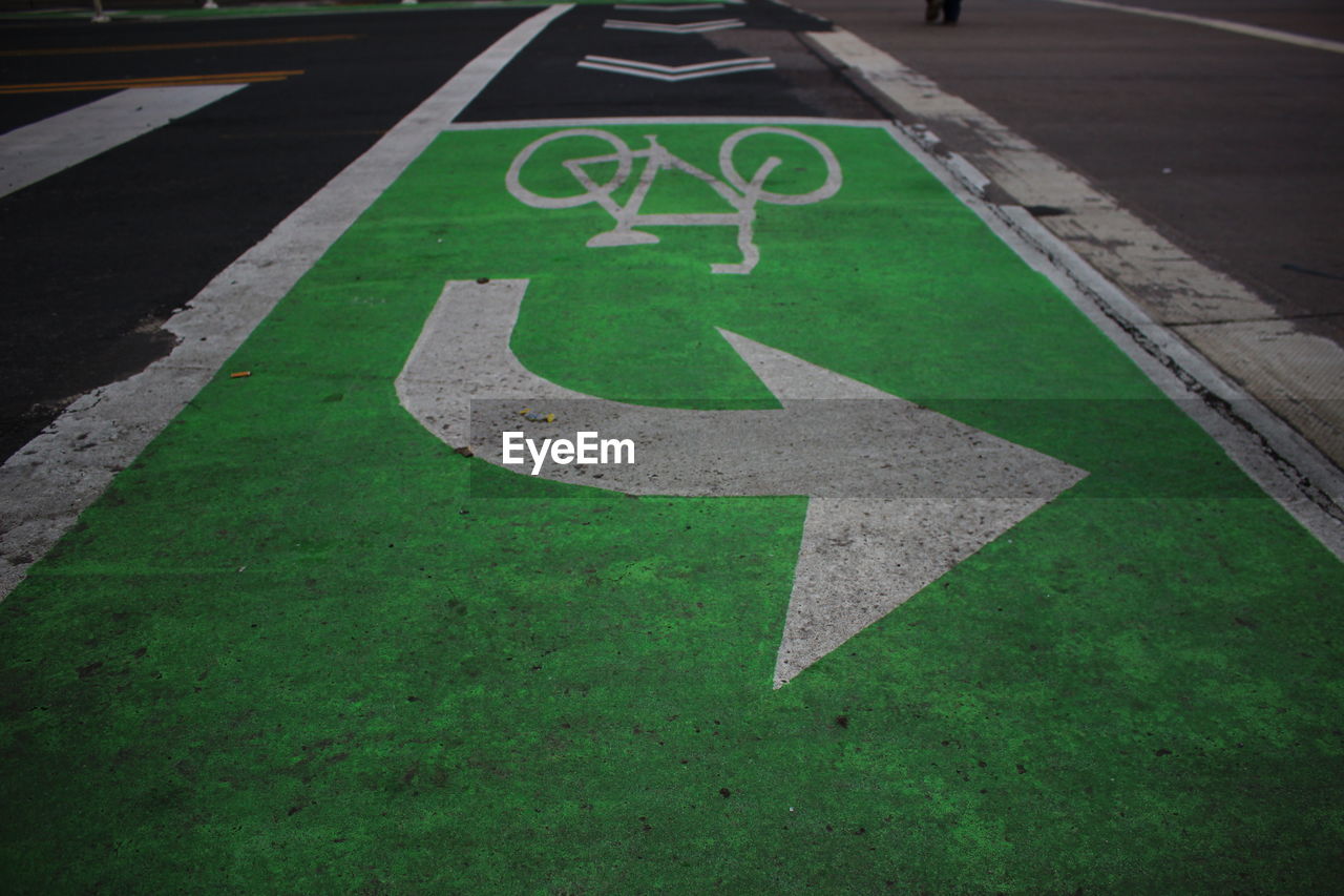 High angle view of arrow and bicycle lane sign on road