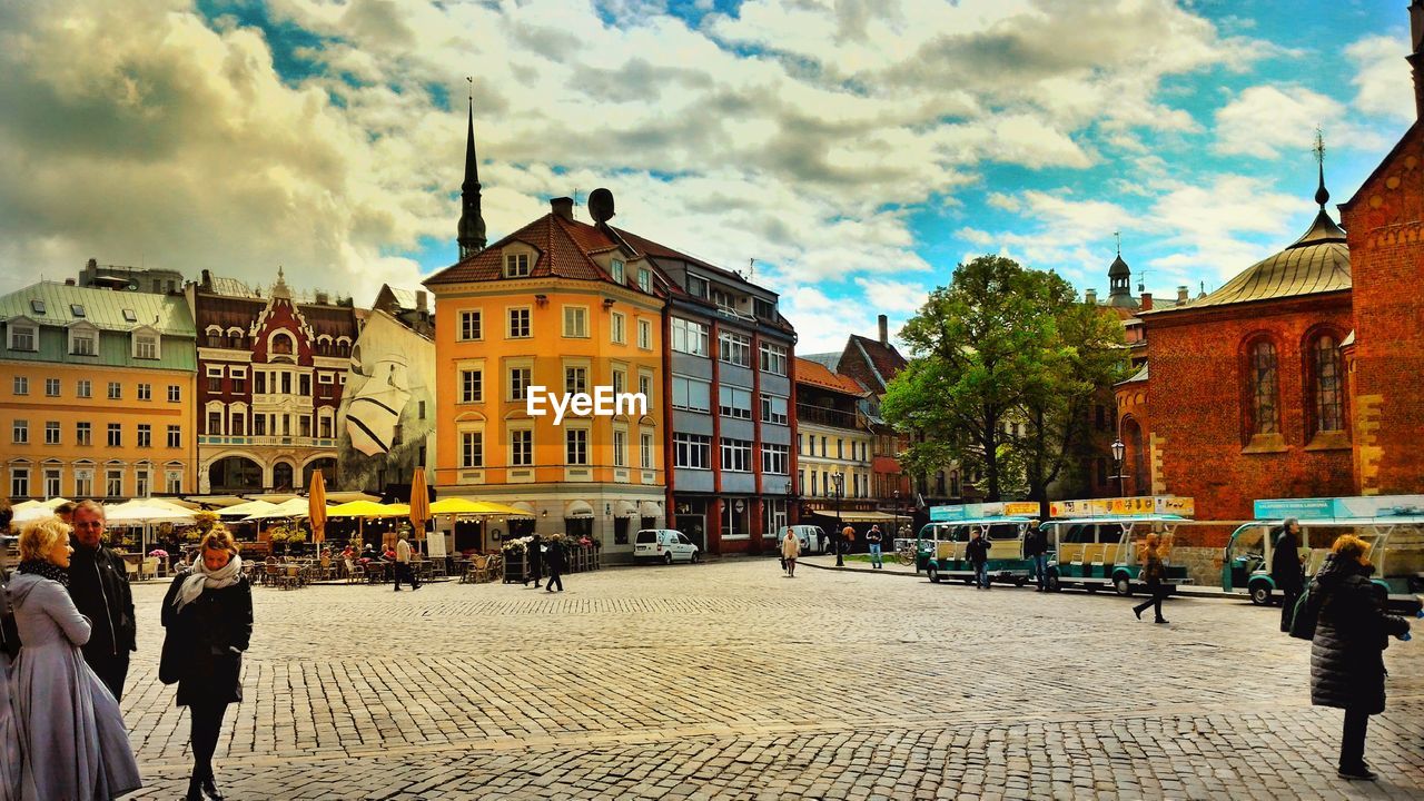 PEOPLE WALKING ON STREET IN CITY AGAINST SKY