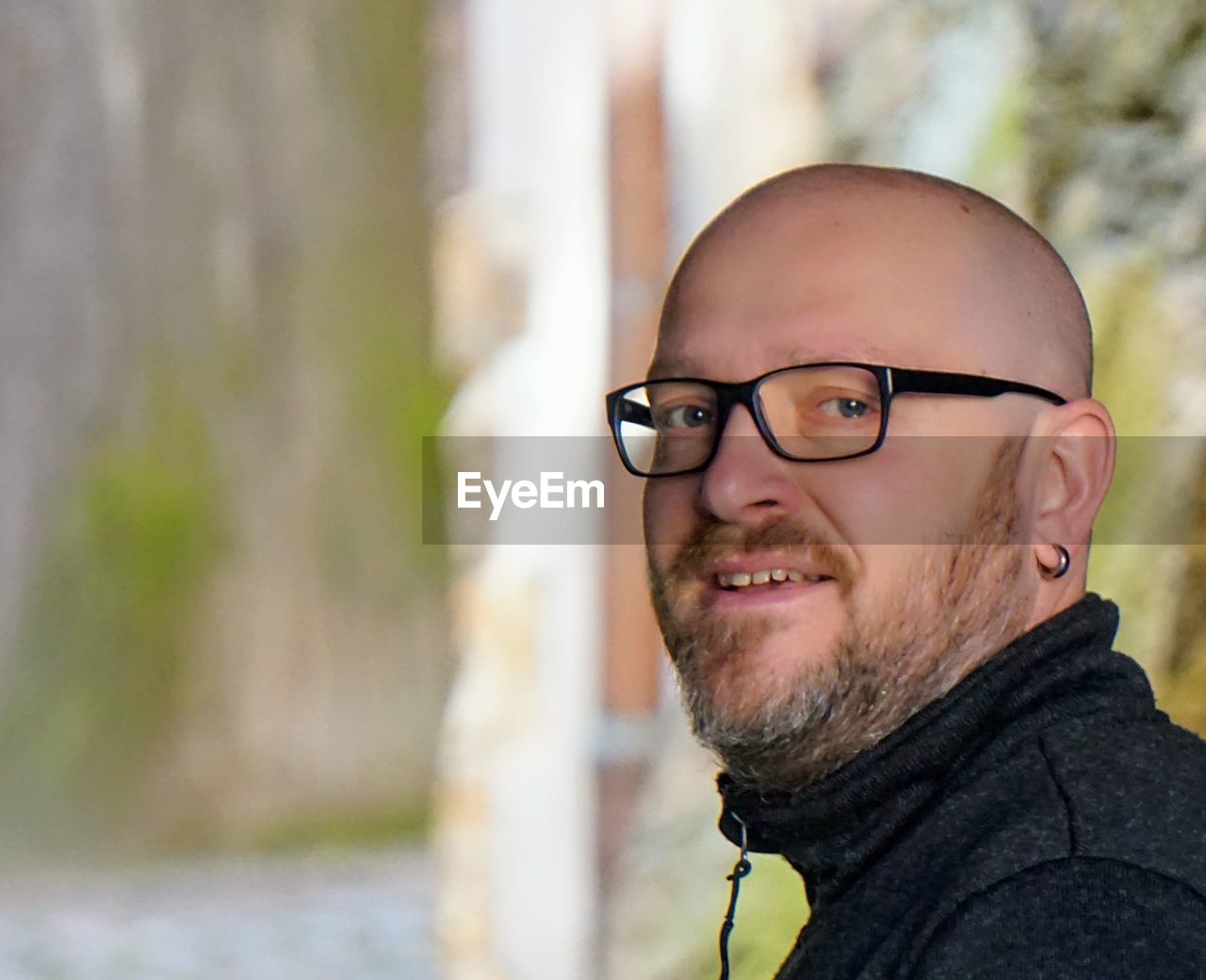 Side view portrait of smiling bald man wearing eyeglasses outdoors