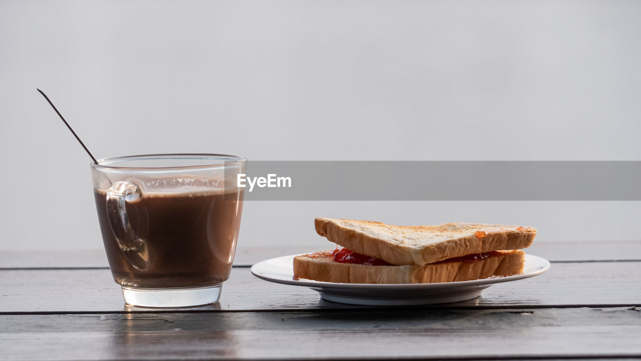 CLOSE-UP OF COFFEE CUP AND WINE ON TABLE