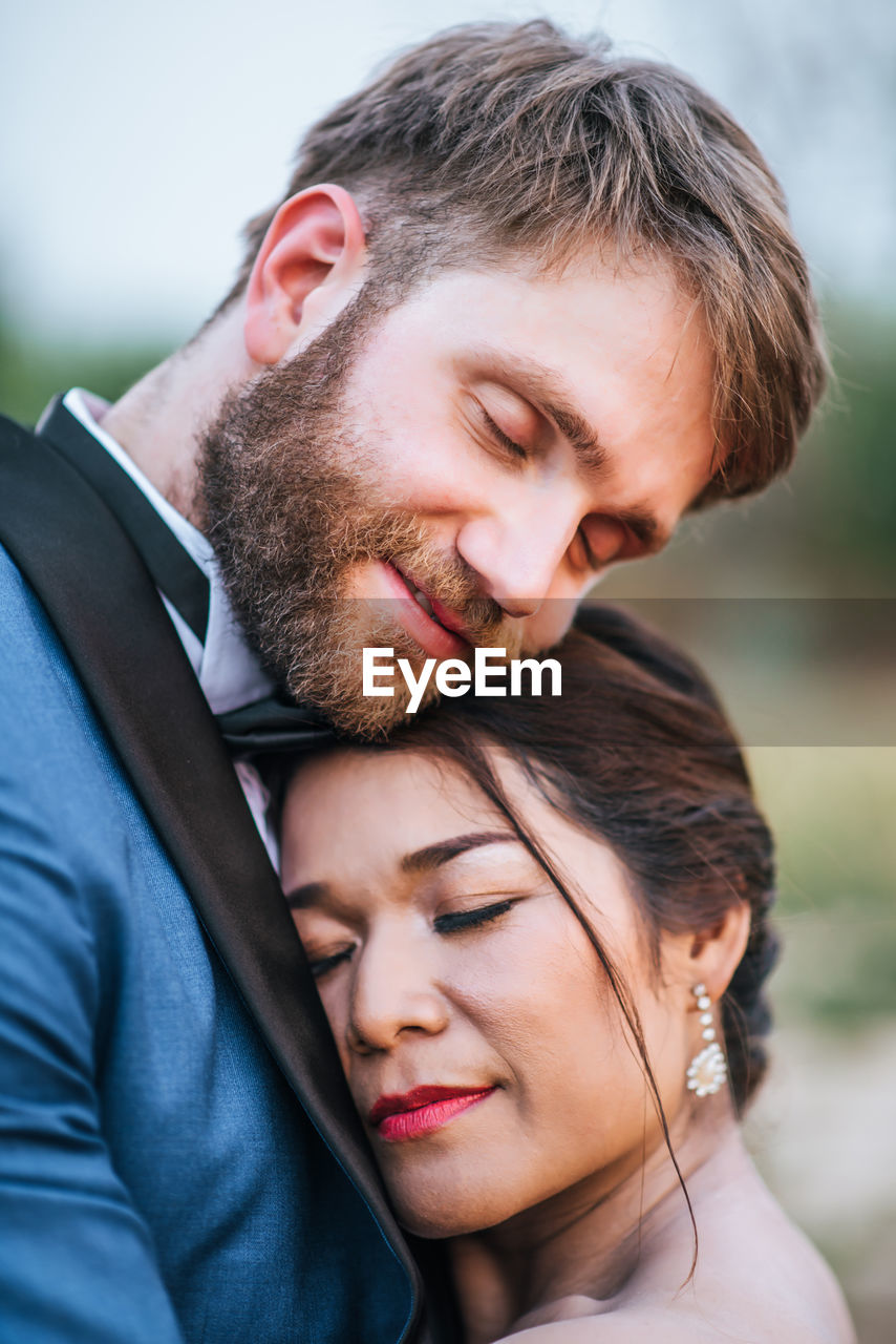 Smiling newlywed couple embracing with eyes closed