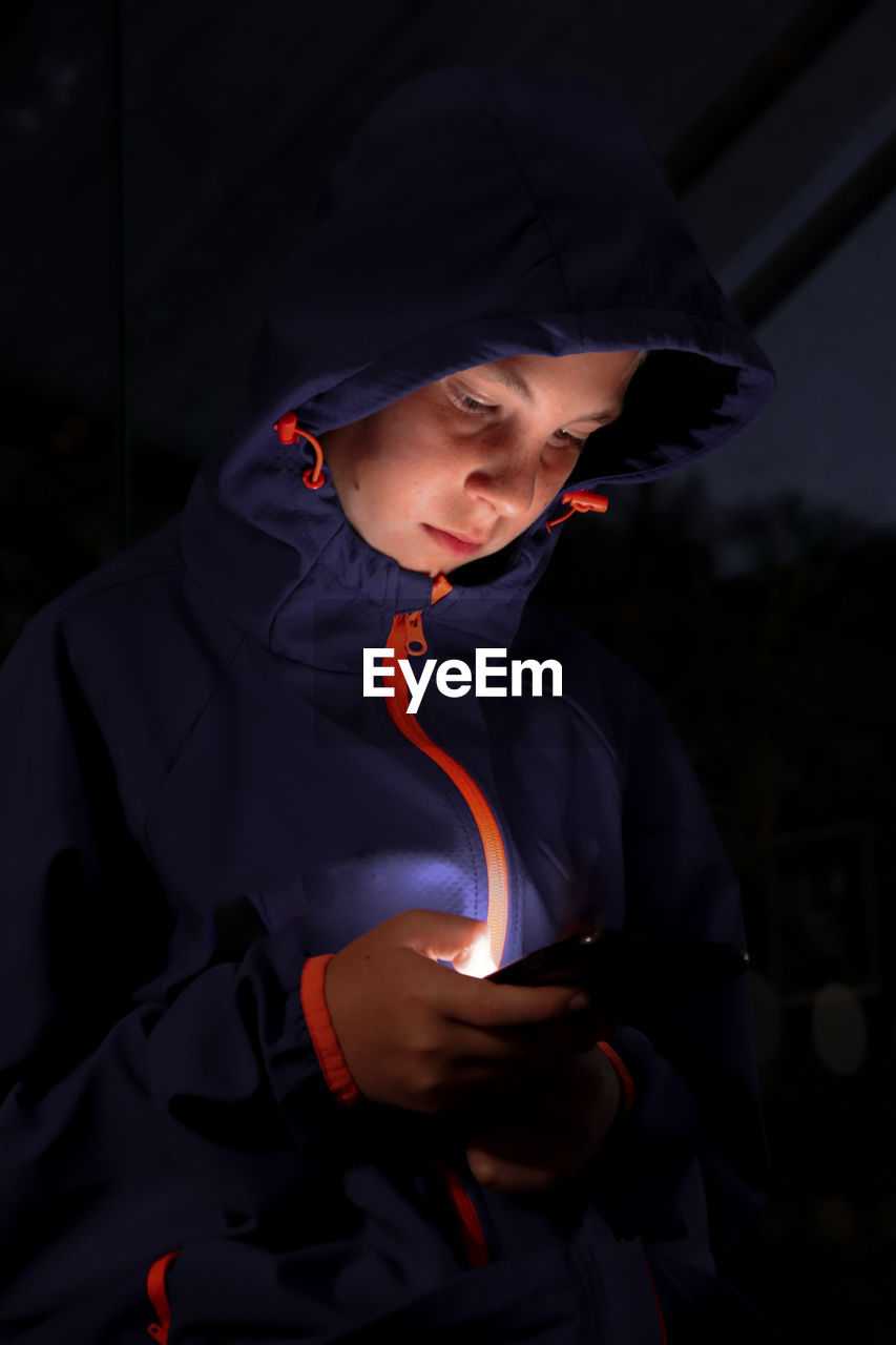  night shot - boy with hoodie on looking at mobile phone with illuminated face