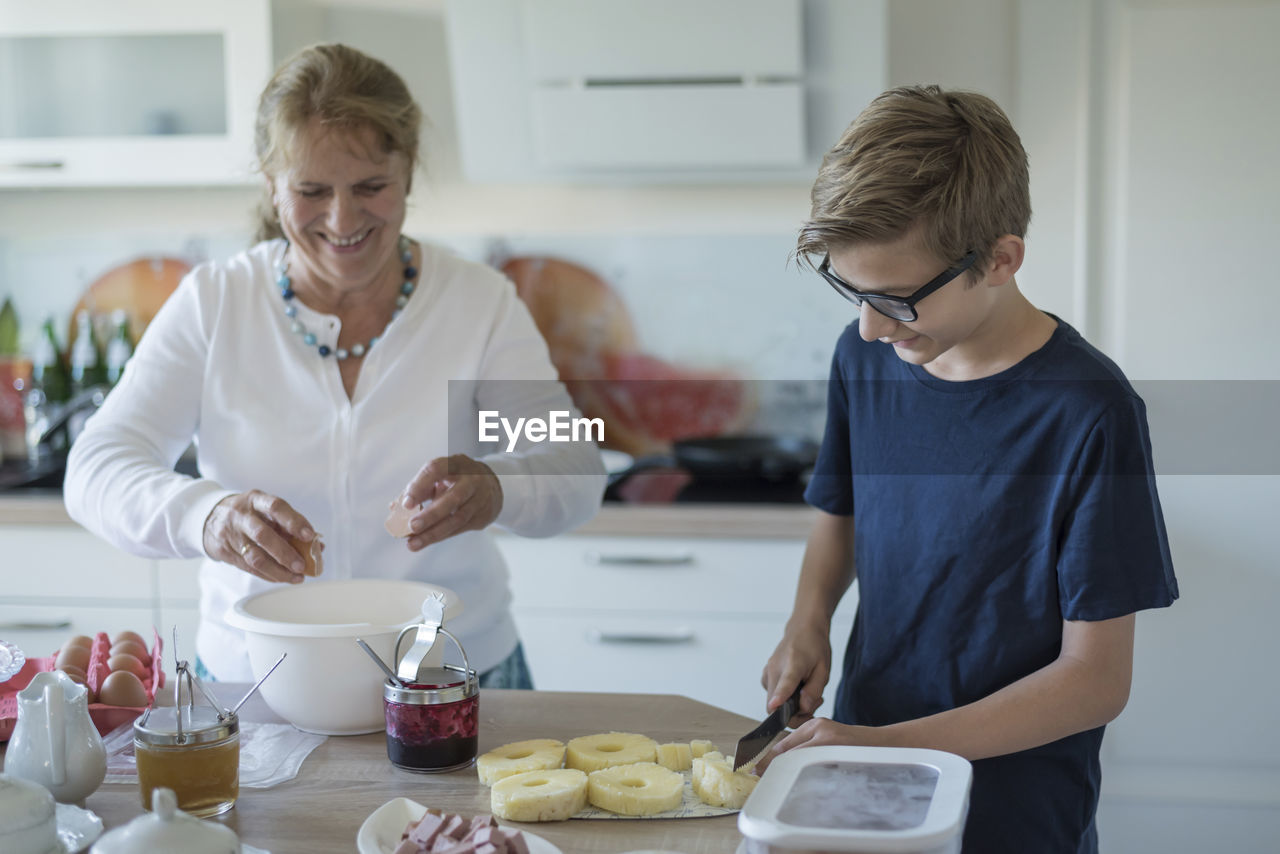 Grandson helping grandmother in kitchen