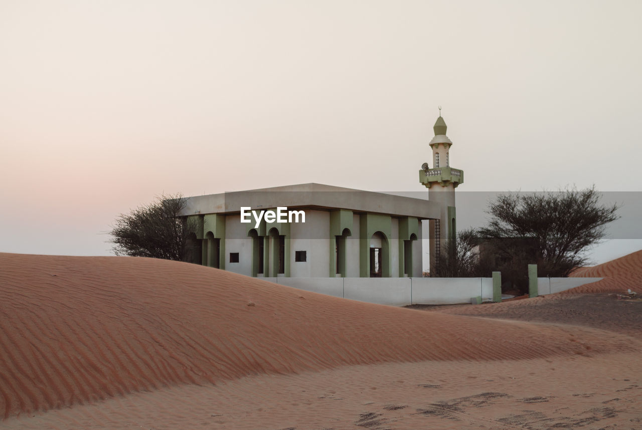 Mosque in desert against clear sky