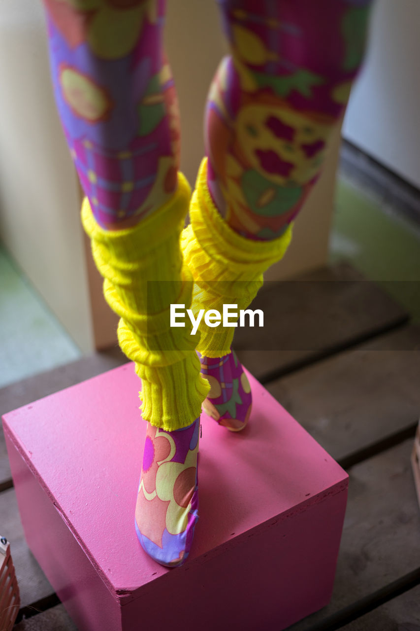 LOW SECTION OF WOMAN STANDING ON PINK TILED FLOOR