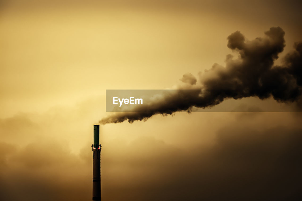 Smoke emitting from chimney against sky