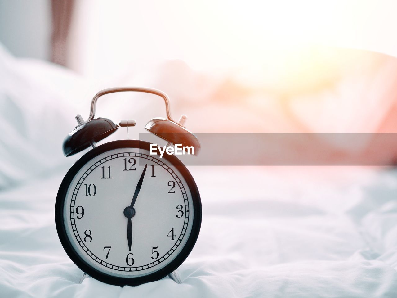 Close-up of alarm clock on bed at home