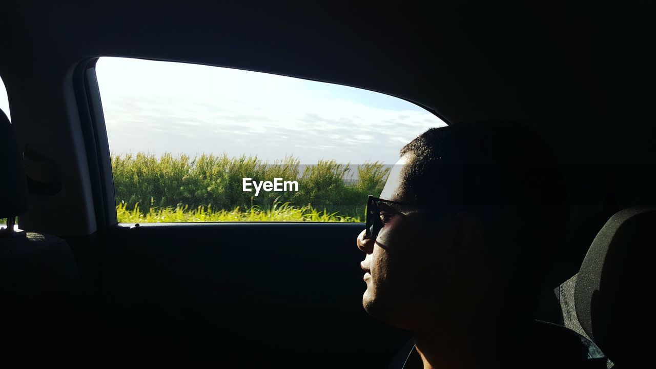 Man sitting by window while traveling in car