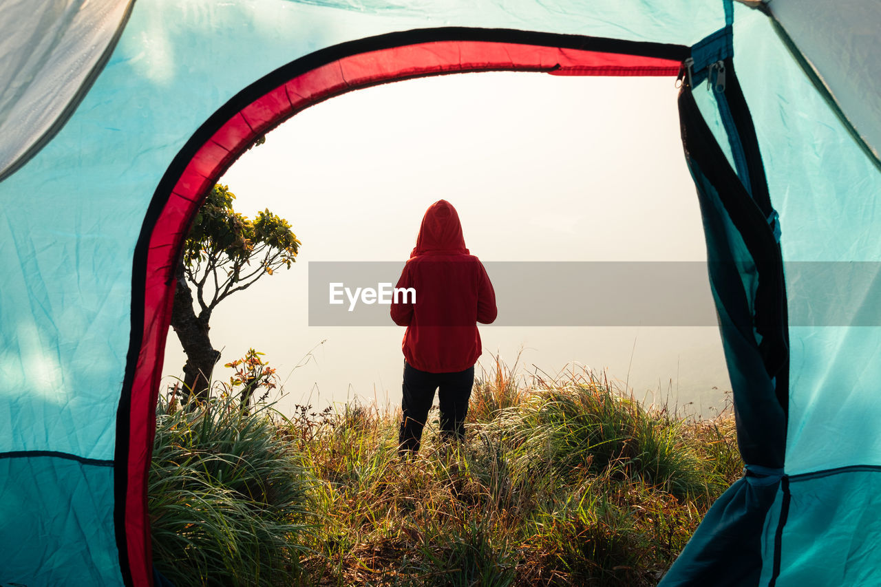 Rear view of man standing on field seen through tent