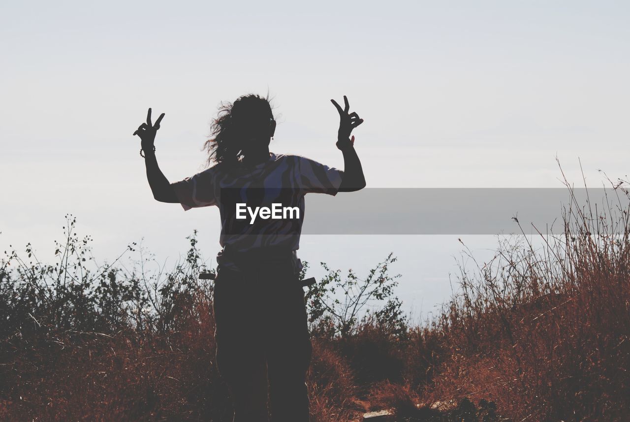 one person, sky, nature, arm, standing, silhouette, morning, land, adult, arms raised, field, limb, rear view, plant, landscape, environment, outdoors, human limb, lifestyles, women, leisure activity, grass, rural scene, three quarter length, beauty in nature, person, men, emotion, young adult, arms outstretched