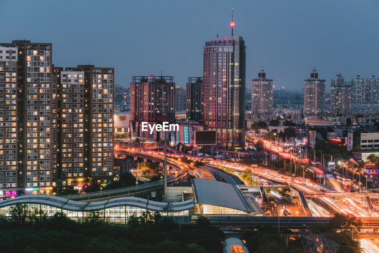 ILLUMINATED MODERN BUILDINGS IN CITY AGAINST SKY IN BACKGROUND