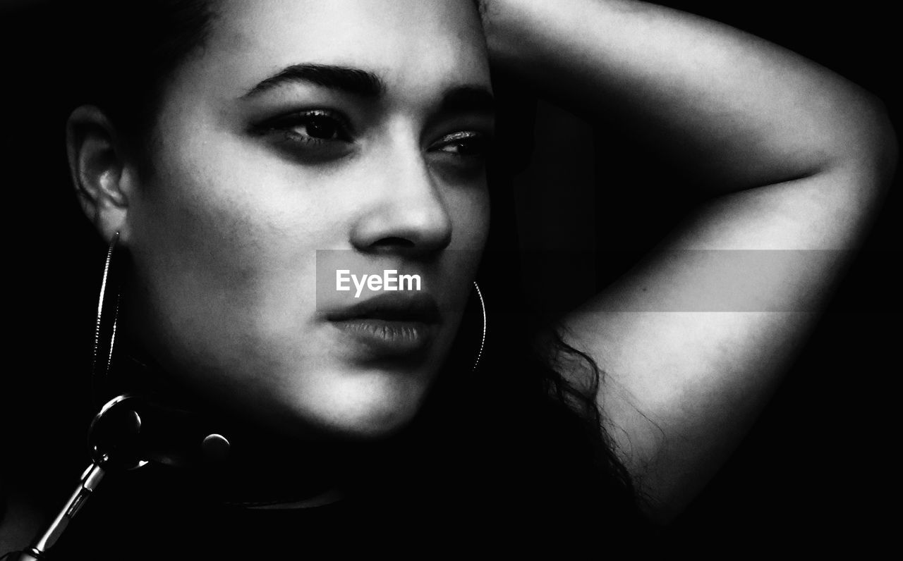 Close-up of young woman against black background