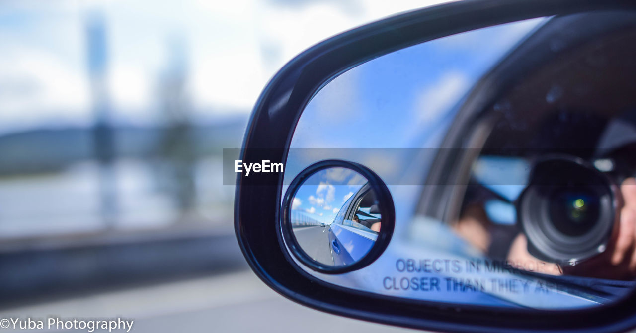 CLOSE-UP REFLECTION OF CAMERA ON SIDE-VIEW MIRROR