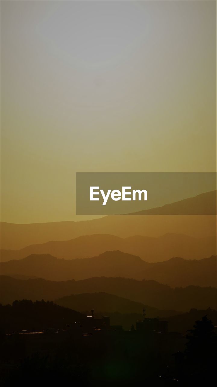 SCENIC VIEW OF SILHOUETTE MOUNTAINS AGAINST CLEAR SKY DURING SUNSET