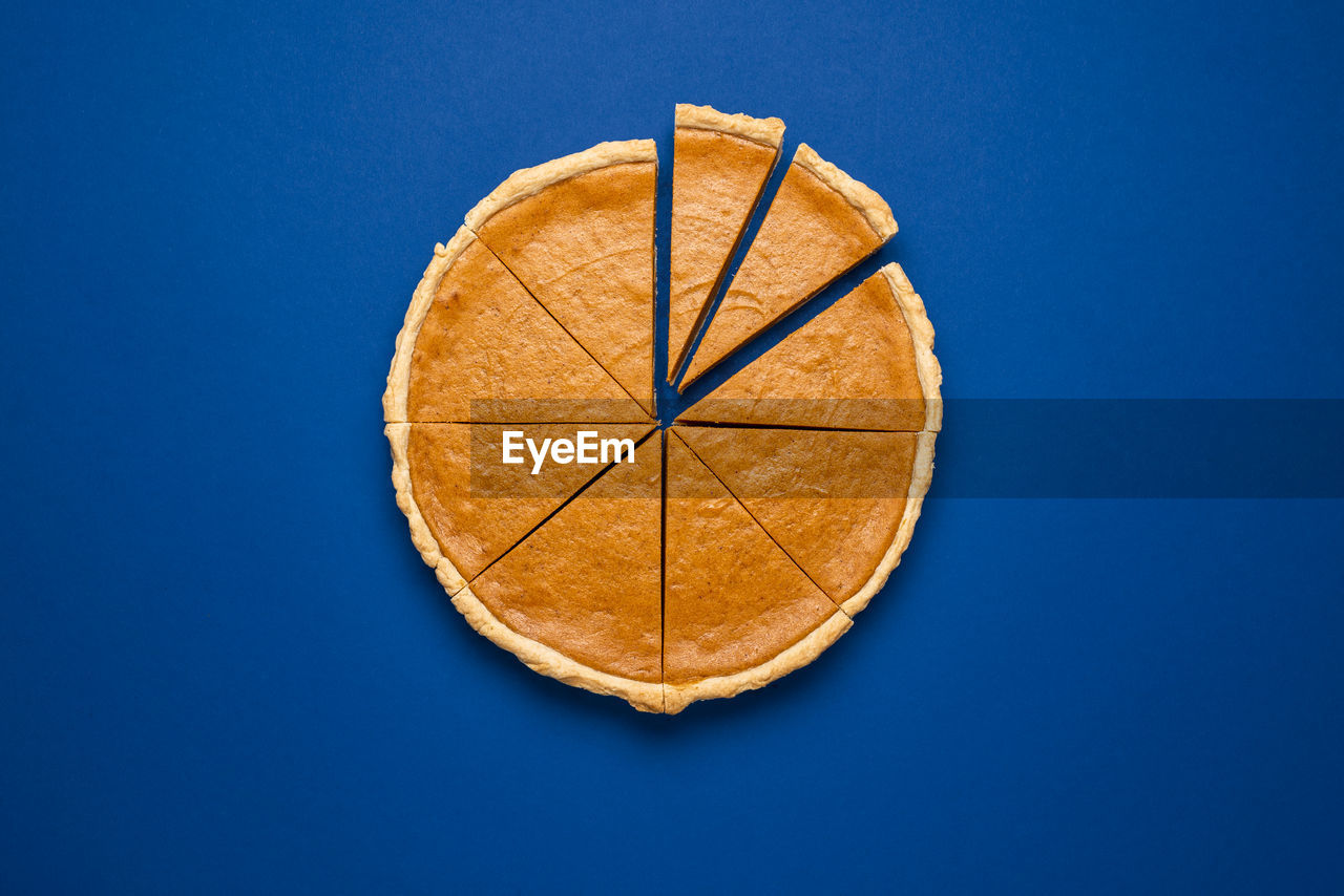 Above view with sliced pumpkin pie on a blue background. thanksgiving traditional dessert. flat lay