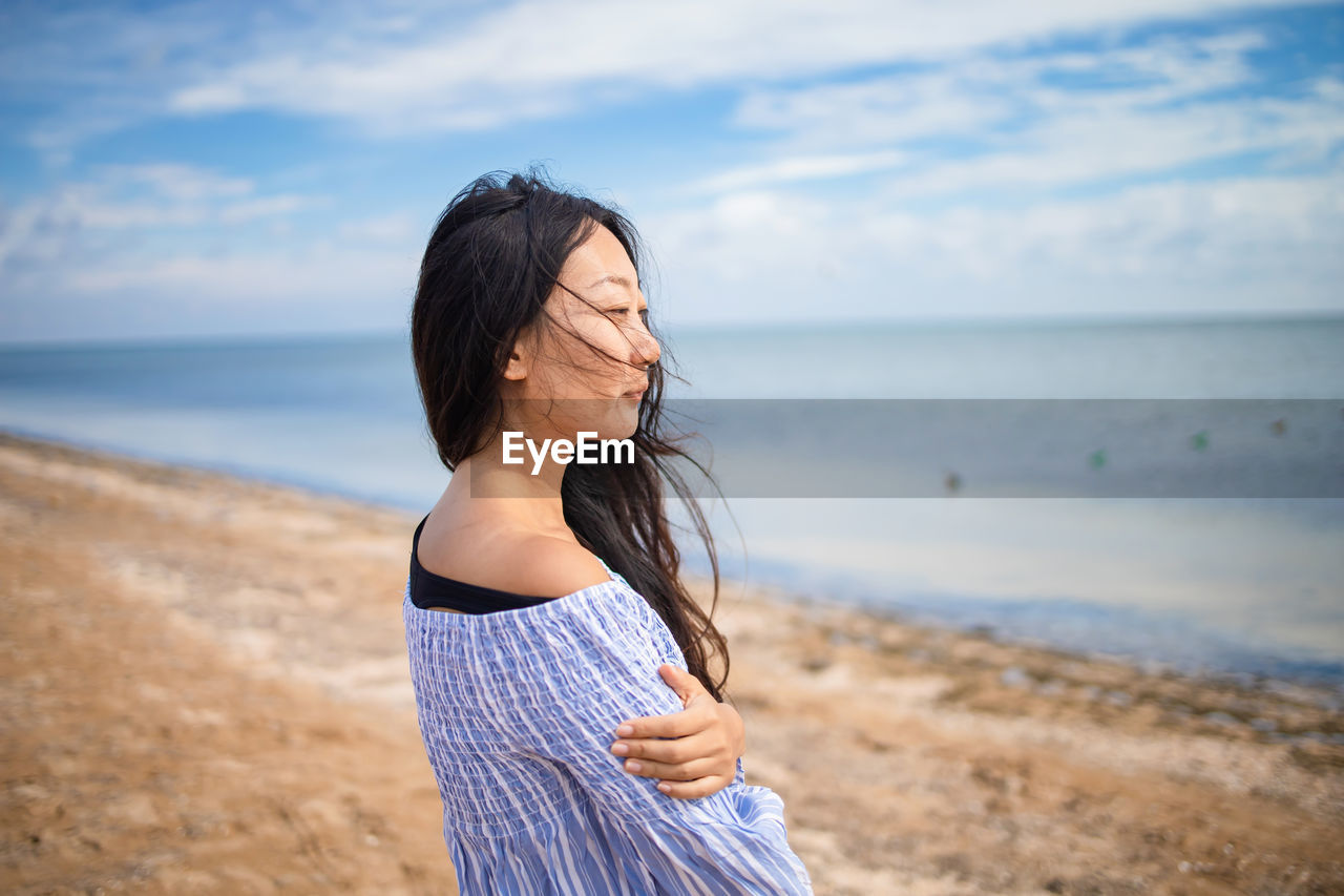 Calm asian woman enjoying sea view on beach