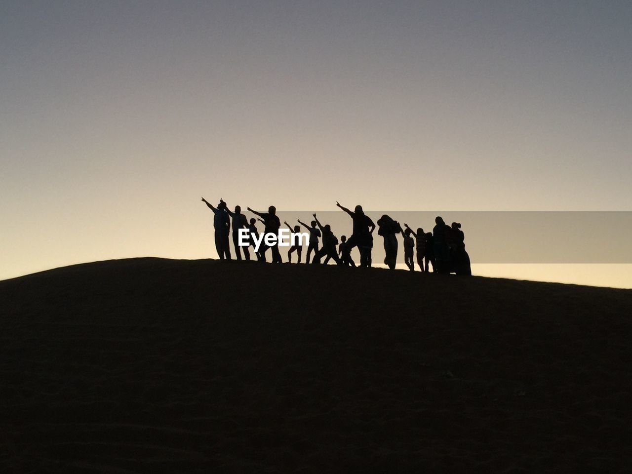 Silhouette people on desert against clear sky