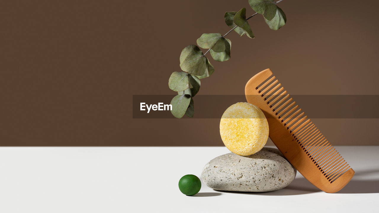 Modern geometric still life composition of a solid shampoo bar. stone and wooden comb balancing