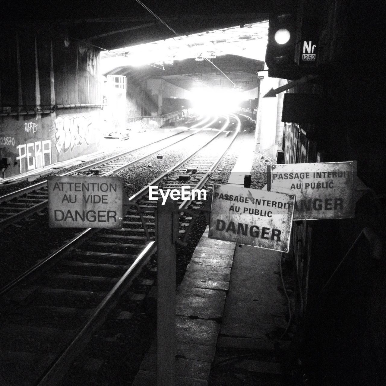 Various sign boards by railroad tracks in illuminated tunnel